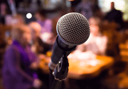 Mikrofon vor unscharfer Partykulisse als Motiv für die Best-of-Karaoke-Liste