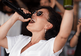 Singende Frau mit Mikrofon als Motiv für die Karaoke-Liste nach Titel