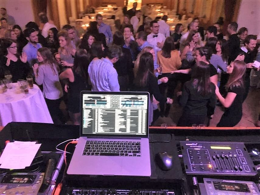 DJ-Pult mit Laptop vor einer gefüllten Tanzfläche als Motiv für die Musik Ihrer Feier
